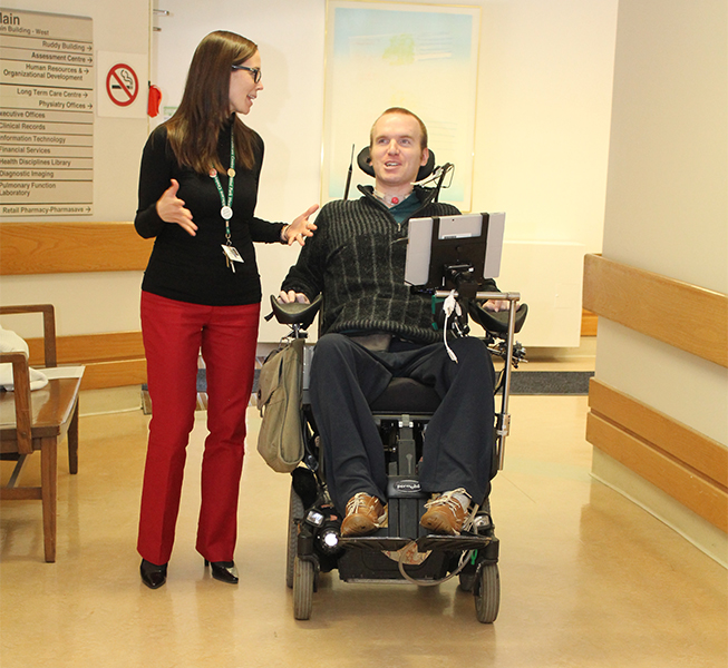 Woman walking beside man in wheelchair